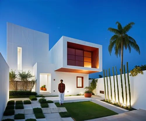 a man in a brown jacket standing in front of a house at dusk,modern house,modern architecture,cube house,mahdavi,piramal,ramoji