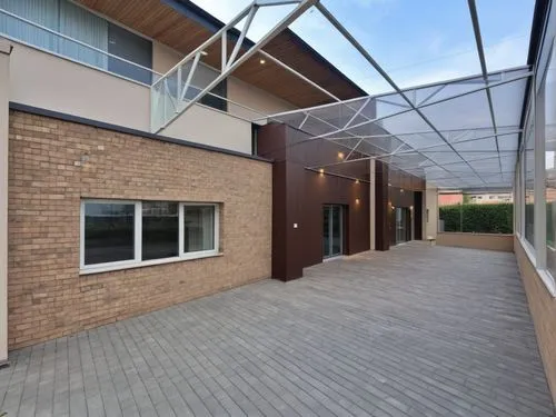 The wall is made of beige stone blocks, up to the windows, then the walls are covered with beige plaster. WINDOWS WITH white FRAMES and an entrance door, the roof is structurally COVERED WITH TRANSPAR