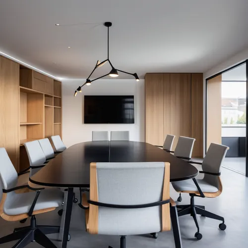 meeting room, white stucco walls, microcement flooring. A table with a black lacquered top and dark wooden legs in the center, eight chairs with wheels with metal structure and seat and back in black 