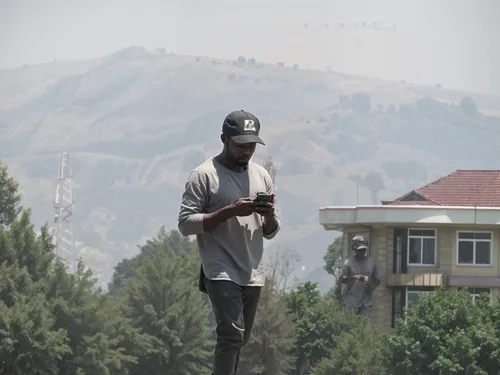 man on skateboard checking his cell phone while overlooking trees and hills,jeremih,thebe,calabasas,gedman,thimphu,ameer