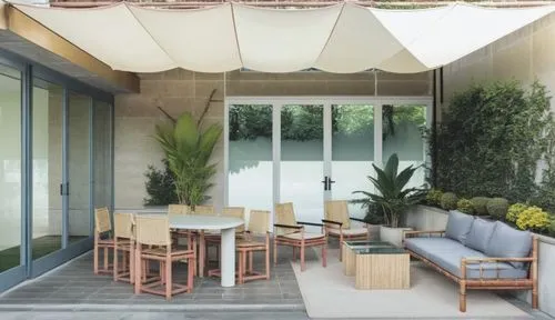 daylight scene of a 1st floor patio from a 7 floor building with white awning. neutral colors. concrete walls and plant pots.  sissal rug under bamboo sofa with with cushions. bistrot table with natur