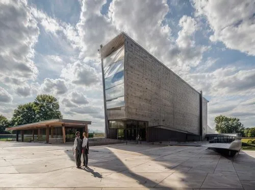 a man standing next to a building with a sky background,christ chapel,chancellery,jasenovac,holocaust museum,snohetta,dupage opera theatre,Architecture,General,Brutalist,Brutalist Classicism