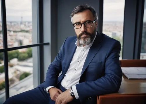 Middle-aged man, certified Heroku architecture designer, serious facial expression, black-rimmed glasses, short brown hair, beard, white button-down shirt, dark blue blazer, fitted trousers, black lea