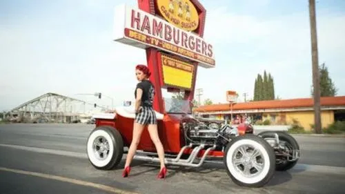 a woman with red heels stands on an old - fashioned truck,quadricycle,hotrod car,old model t-ford,shriner,terraplane,chicanos