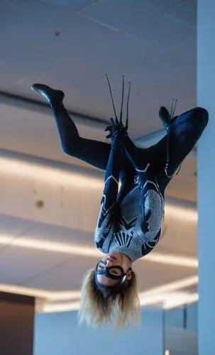 a photography of a beautiful caucasian blonde girl 22 years old, she is wearing a black mask and a black and white suit of spider woman of Marvel, she is head stop holding whit your hands some cables 