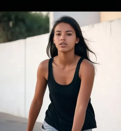 The Moroccan girl, about 18 years old, tanned, straight black hair, wears sneakers, a tank top and black shorts.  A woman in love walks down the street at sunset.,a woman is walking on a city street,n