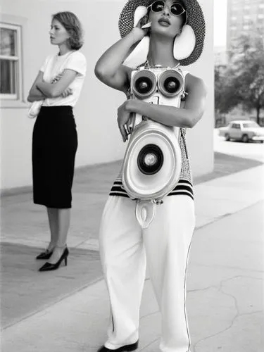 Two different women.,woman in fashion outfit with speakers standing on sidewalk,chicanas,retro woman,retro women,joan collins-hollywood,sixties,vintage fashion,Photography,Black and white photography,