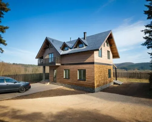 a large wooden home sits on a gravel road next to a parked car,timber house,wooden house,inverted cottage,log home,the cabin in the mountains,log cabin