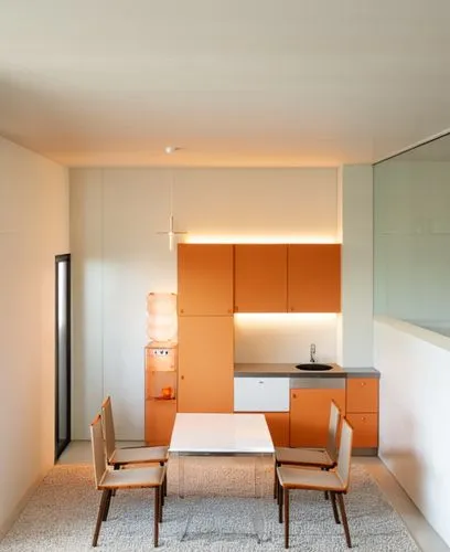 Beige kitchen set, white countertop, stone wall panel, modern water cooler, white table with wooden legs and chairs with soft orange seats. Above the table is a chandelier made of transparent glass ba