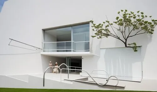 UNA CASA  ESTILO MINIMALISTA CON UN MURO DECORADO CON UNA JARDIENRA CON PLANTAS DE FORMIO, UN GRAN ARBOL SALE DE LA BARDE QUE LIMITA LA CASA, UNA GRAN PUERTA DE MADERA DE CEDRO DE ACCESO, Y EN LA PLAN