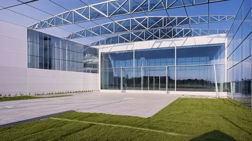 an empty office building with grassy area in front,glass facade,structural glass,novozymes,glass building,phototherapeutics,technopark,etfe,genzyme,metaldyne,epfl,company headquarters,audencia,globalf