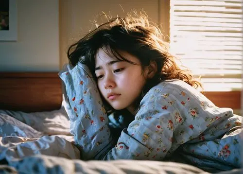 Sleepy teenager, messy bedhead, lazy morning eyes, pale skin, dark circles under eyes, worn-out pajamas, crumpled sheets, scattered pillows, cluttered bedside table, dimly lit room, warm sunlight peek