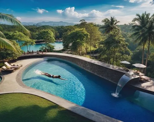 people swimming, lush green and trees in the background and with swimming pool lightings,a large pool with a waterfall is surrounded by trees,infinity swimming pool,outdoor pool,swimming pool,ubud,phi