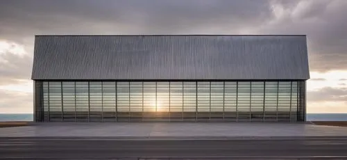 the building texture is steel and the side is open there is no materials and the background is comfortable for the eye,hangar,glass facade,metal cladding,mclaren automotive,rubjerg knude lighthouse,cl