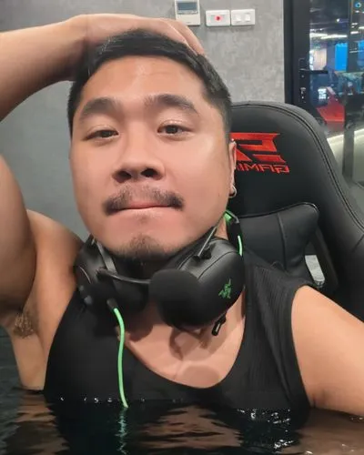 soaking wet sweaty naked body of an average asian young daddy, a little bit chunky and masculine, a little bit fat, fluffy belly, hairy, large penis, sitting with both legs being hold straight up and 