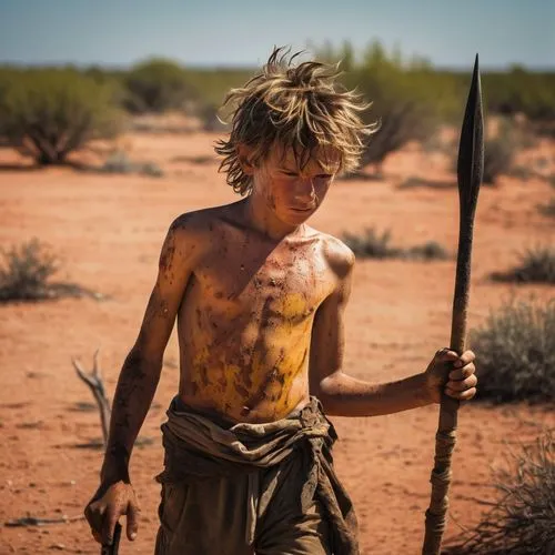 Shirtless sunburn barefoot filthy dirty angry young boy in the wild holding a spear with messy hair covered in sweat dirt and scars in bright sunshine in blazing heatwave sneaking around hunting in th