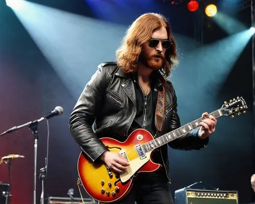 Un hombre alto, de unos 20 años de edad, cabellos largos y lisos de color rojizo, barba, chaqueta de cuero estilo años 1970 y con lentes de aviador, toca la guitarra en frente del público. Él va tocan