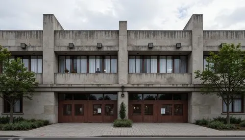 Rugged elementary school facade, brutalist architecture, raw concrete walls, fortress-like structure, asymmetrical composition, bold geometric shapes, industrial-style windows, metal grilles, weathere