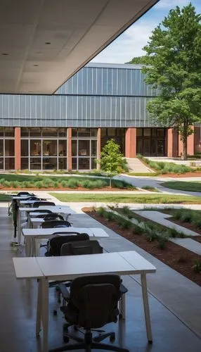 Auburn University, College of Architecture Design and Construction, modern building, red brick exterior, white columns, glass walls, steel beams, large courtyard, lush greenery, walking students, back