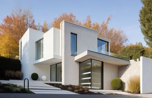 DISEÑO EXTERIOR DE UNA CASA ESTILO MINIMALISTA,  CON USO DE  COLORES BLANCO Y UN MURO DE MARMOL TRAVERTINO, VENTANAL EN EN ESQUINA Y CANCELES DE ALUMNIO Y CRISTAL, PUERTAS DE MADERA, UBICADA EN UN ENT