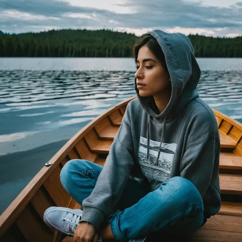 woman in gray hoodie sitting on brown wooden boat on lake during daytime,girl on the boat,meditating,meditation,girl on the river,meditative,perched on a log,meditate,canoe,wooden boat,rowboat,peace o