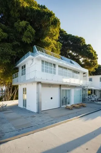 café with outdoor tables and chairs at the entrance, seating on the second-floor balcony, glass rail ,mid century house,dunes house,beach house,cube house,aqua studio,commercial building,termales baln