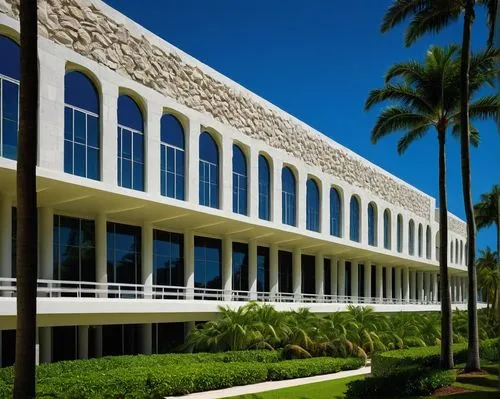 University of Miami School of Architecture, modern building, palm trees, sunny day, blue sky, white columns, glass windows, stone walls, lush greenery, tropical landscape, people walking in the backgr