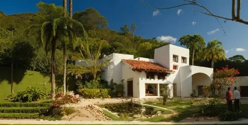 EL EXTERIOR DE UNA CASA CON ESTILO MEXCANO MODERNO, USO DE COLORES VIBRANTES, MATERIALES REFIONALES, TEJA, VIGAS DE MADERA, EN UN AMBIENTE EXUBERANTE, ESTANQUE DE AGUA AL FRENTE.,a person stands in fr