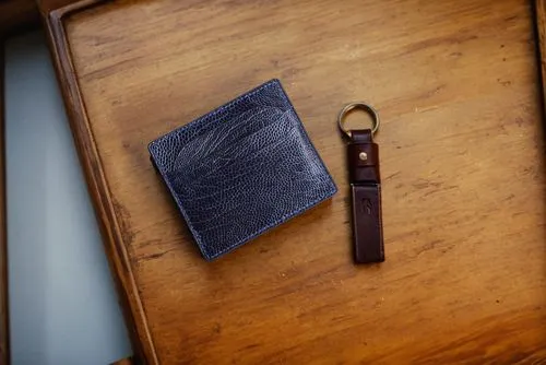 a note pad with a key ring sits on a wooden desk,waterfield,clip board,leather goods,noteholders,pocket flap,wooden clip