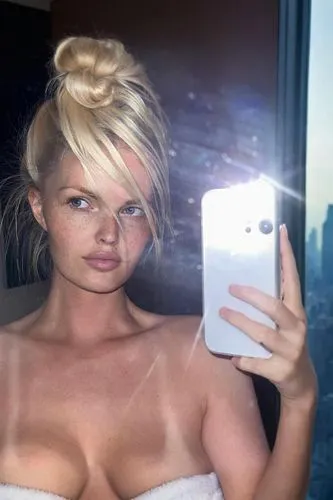 girl taking a selfie with her phone, window, new-york city, hotel room, high-bun hairstyle, thick fluffy white towel around chest,sirotka,sunburned,sunburnt,suntanned,sunburns,strapless,tetas,burning 