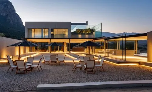 "Exterior image of an event venue in Bermejo, Tarija, captured on a summer day. The building features walls of natural stone, tempered glass, exposed concrete, and salt walls. The spaces are spacious,