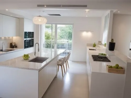 A modern kitchen design where all the cabinets are in a clean white color, and the countertop is also white. The kitchen features sleek, minimalist lines with smooth, handleless cabinets. There's a la