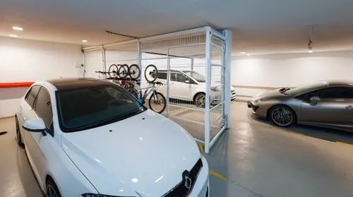 two cars in a garage, one is white with black lettering,garage,underground garage,vehicle storage,car showroom,garages,parking system,Photography,General,Realistic