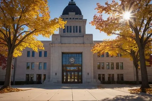 Nebraska City Hall, modern architectural design, grand entrance with glass doors, symmetrical stone facade, clock tower, ornate details, American flags, city square, autumn trees with yellow leaves, a