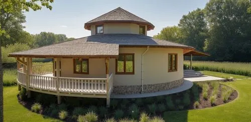 small modern house surrounded by a garden.
The walls are white. Gray roof.,a large round home sitting on top of a lush green field,round house,gazebo,summer house,round hut,summerhouse,pool house,Phot