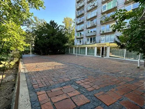 поменять на уличную брусчатку,a street with brick pavement in front of a tall building,paved square,paving stones,pavers,patio,paving slabs,the block of the street