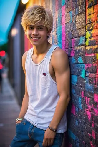 Shota boy, twink, sparkling eyes, bright smile, blonde hair, messy bedhead, lean chest, skinny legs, denim shorts, white tank top, sneakers, leaning against a wall, hand in pocket, casual pose, urban 