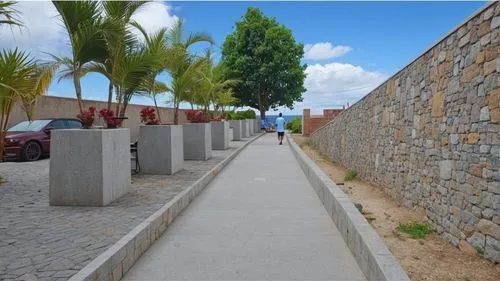 two people are walking down a walkway next to a brick wall,city walls,city wall,fort of santa catalina,dodoma,portoviejo,tunja,Photography,General,Realistic