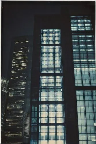 Modern, futuristic, glass, steel, sleek, minimalist, urban, skyscraper, office building, angular lines, geometric shapes, LED lights, nighttime, cityscape, busy streets, reflections on windows, symmet