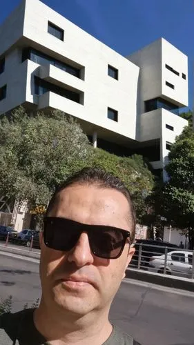 modern cubic white stone building,a man wearing sunglasses and smiling for the camera,macba,tel aviv,dizengoff,cube house,morphosis,cubic house