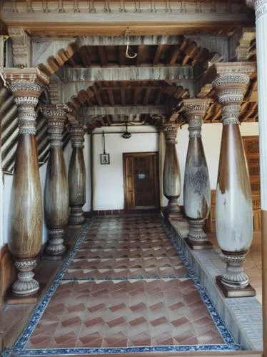 Beautiful carved teakwood columns bottom with stone carvings, redoxide flooring on center and  terracotta coloured  tiles in boder of flooring,  white paint for walls and royalblue paint for walls bod