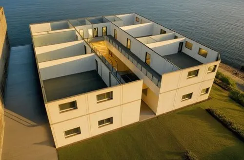 escuela con volumen geometrico de alto relieve, diferente caida de agua en techo con camino en la entrada,cube stilt houses,cubic house,dunes house,habitat 67,cube house,coastal protection,modern arch