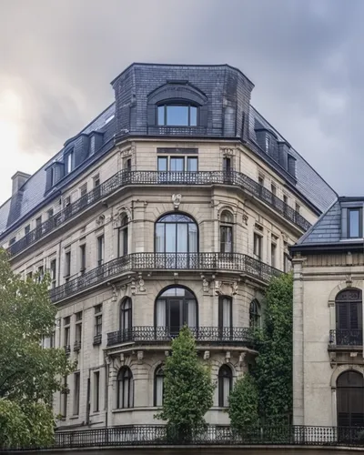 a Renaissance building with a sandstone base and the upper floors in white plaster, with several worked frames, the windows on the upper floors have a balcony in front with black iron guards, the wind