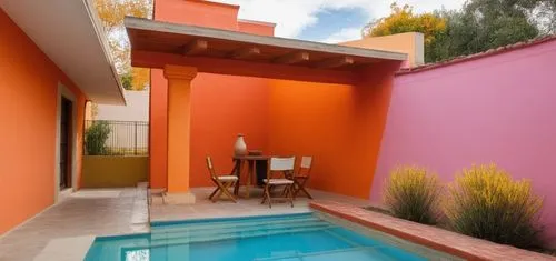 REMODELACION DE UNA CASA CON ESTILO MEXICANO, USO DE COLORES VIVOS, MADERA, PISOS DE BARRO, FLORES Y UN ESPEJO DE AGUA CON FUENTE EN UN MURO,a small pool in a patio area with table and chairs,landscap