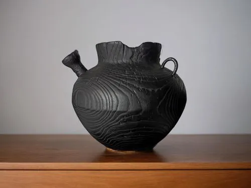 ваза стоит на деревянном столе и на заднем фоне белая стена,black vase with handle sitting on wooden shelf,vase,clay jug,jug,wine jug,amphora,fragrance teapot