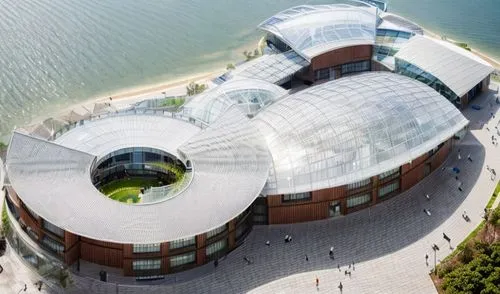 a biodiversity research centre with aluminium panel roofing and shaded with glass panels, with mangroves surrounding it,autostadt wolfsburg,ozeaneum,mercedes-benz museum,musical dome,planetarium,bunde