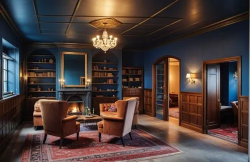 A cozy, gothic Victorian sitting room with a fireplace, concrete floor, wallpaper, cove lighting, medium wood paneling, oriental carpet, crystal chandelier,blue room with two chairs and a rug,blue roo