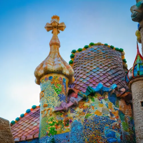 overview of a castle designed by Antonio Gaudi, Organic and Natural Forms, Unique and Unconventional Structures, Exquisite Detail and Ornamentation, Vibrant colors and use of mosaic, Exploration of Li