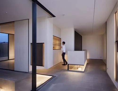 interior , lobby , concrete , black window frame,there is a man standing next to a counter in the room,modern minimalist bathroom,cubic house,hallway space,mirror house,interior modern design,penthous