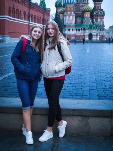 2 pretty girls in the old Russian city centre, wearing knee-length jeans and white American trainers. Their calves are bare and hairy.,two women standing in front of a church,red square,saint basil's 